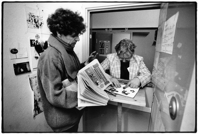 351035 Afbeelding van een dakloze man die zijn geld telt om een stapel daklozenkranten (Straatnieuws) in te kopen bij ...